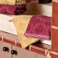 Gants de toilette Néroli en éponge jacquard ciselée, présentés en coloris curry et prune.