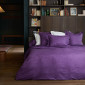 Parure Magnolia en satin de coton jacquard violet, avec taies d’oreiller assorties et motif floral tissé dans la matière.