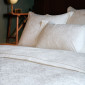 Housse de couette Magnolia en satin jacquard ivoire, mise en scène sur un lit avec les taies d’oreiller assorties.