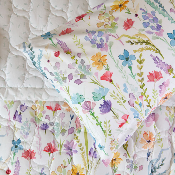 Gros plan sur les fleurs des champs et le piquage en relief du couvre-lit Sophie.