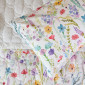 Gros plan sur les fleurs des champs et le piquage en relief du couvre-lit Sophie.